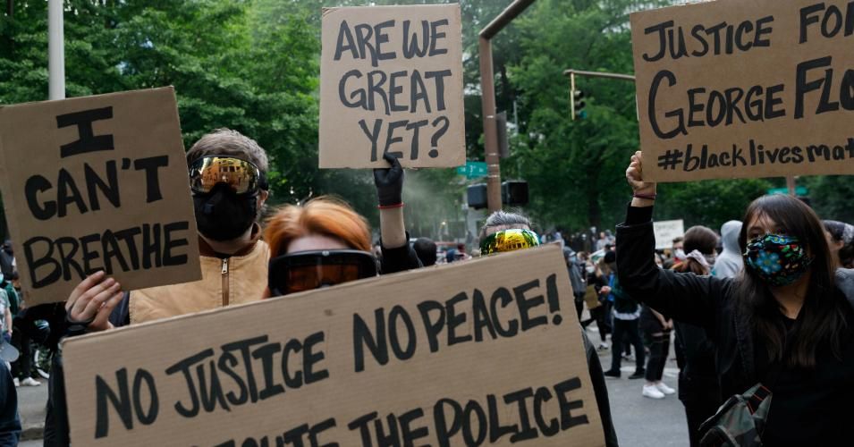 People carrying banners march to protest over the death of George Floydan unarmed black man who died after being pinned down by a white police officer in Minneapolis—on May 31, 2020 in Portland, Oregon.