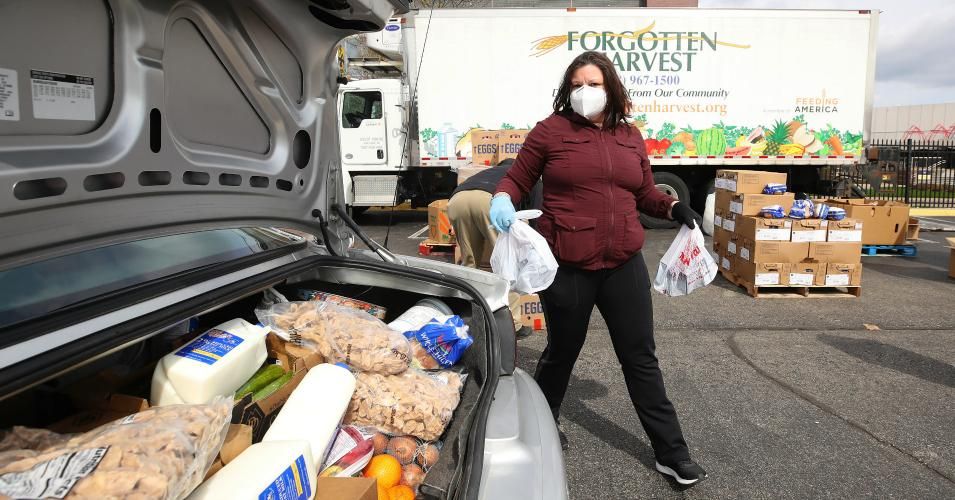A volunteer with Forgotten Harvest loads food into a vehicle at a mobile pantry April 14, 2020 in Detroit, Michigan.