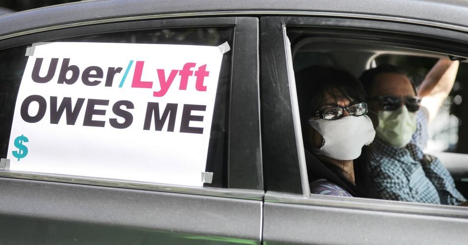 A driver and passenger wear face masks as Uber and Lyft drivers with Rideshare Drivers United and the  Transport Workers Union of America conduct a 'caravan protest' outside the California Labor Commissioner's office amidst the coronavirus pandemic on April 16, 2020 in Los Angeles, California. 