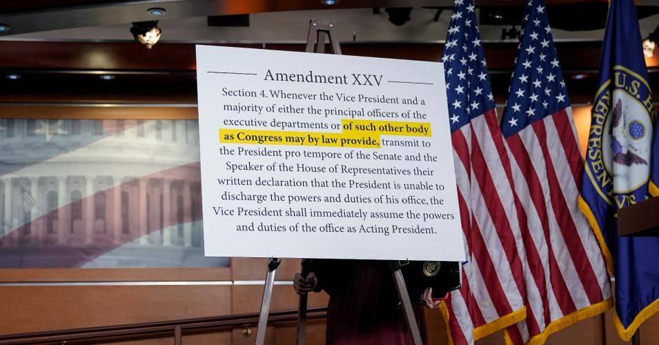 An aide to Speaker of the House Nancy Pelosi (D-Calif.) sets up a sign about the 25th Amendment before the start of a news conference at the U.S. Capitol on October 9, 2020 in Washington, D.C.