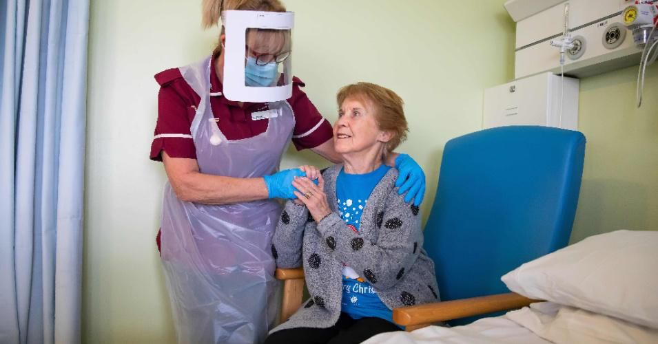 Margaret Keenan, 90, who was the first patient in the United Kingdom to receive the Pfizer-BioNtech Covid-19 vaccine, talks with healthcare assistant Lorraine Hill while preparing to leave University Hospital Coventry on December 9, 2020, a day after receiving the vaccine. (Photo by Jonny Weeks/Pool/AFP via Getty Images)