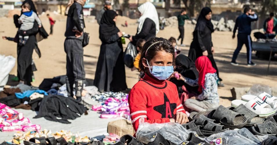 A girl wearing a protective mask amid the Covid-19 pandemic sells shoes at an open-air market in Syria on February 24, 2021. (Photo: Delil Souleiman/AFP via Getty Images)
