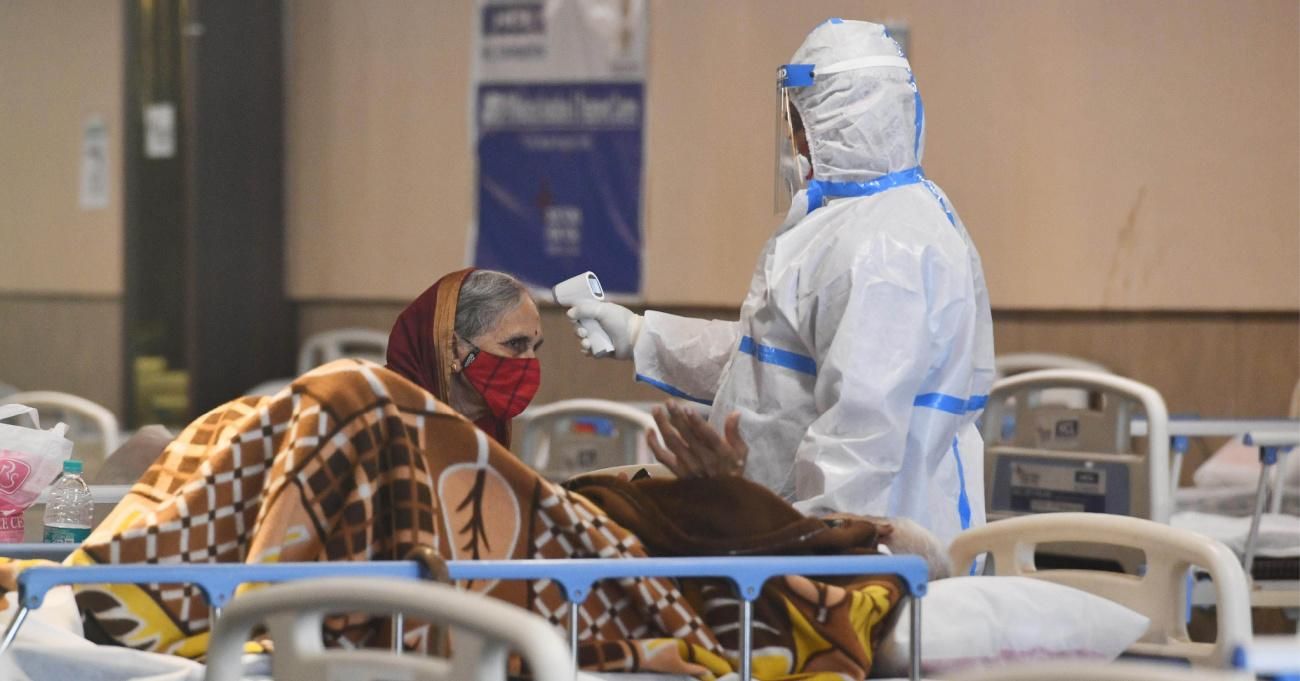 A health worker wearing a protective suit treats Covid-19 patients inside an isolation ward in Shehnai Banquet Hall near government-run Lok Nayak Jai Prakash Narayan LNJP hospital in New Delhi, India, on April 13, 2021.