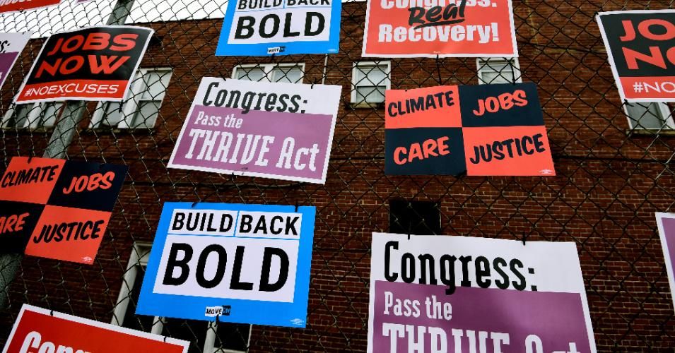 Signs are seen during a community gathering and job fair as West Virginians demand an economic recovery and infrastructure package prioritizing climate, care, jobs, justice on April 8, 2021 in Charleston, West Virginia.