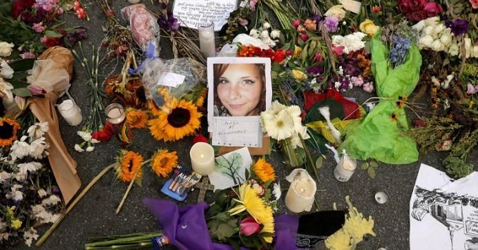 Flowers, candles and chalk-written messages surround a photograph of Heather Heyer on the spot where she was killed and 19 others injured when a car slammed into a crowd of people protesting against a white supremacist rally, August 16, 2017 in Charlottesville, Virginia.
