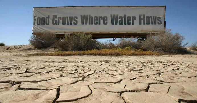 A sign on a farm trailer reading "Food grows where water flows" hangs over dry, cracked mud at the edge of a farm April 16, 2009 near Buttonwillow, California. (Photo: David McNew/Getty Images)