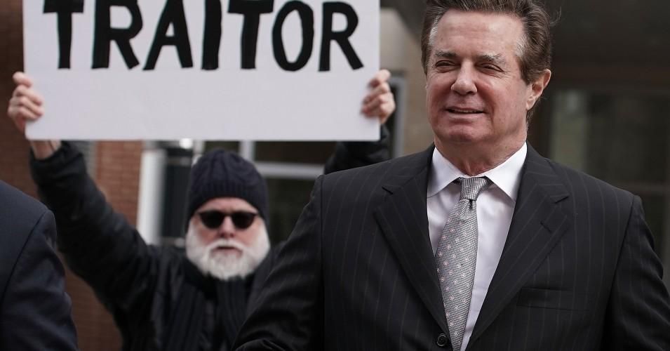 Former Trump campaign manager Paul Manafort (R) arrives at the Albert V. Bryan U.S. Courthouse for an arraignment hearing as a protester holds up a sign March 8, 2018 in Alexandria, Virginia. (Photo: Alex Wong/Getty Images)