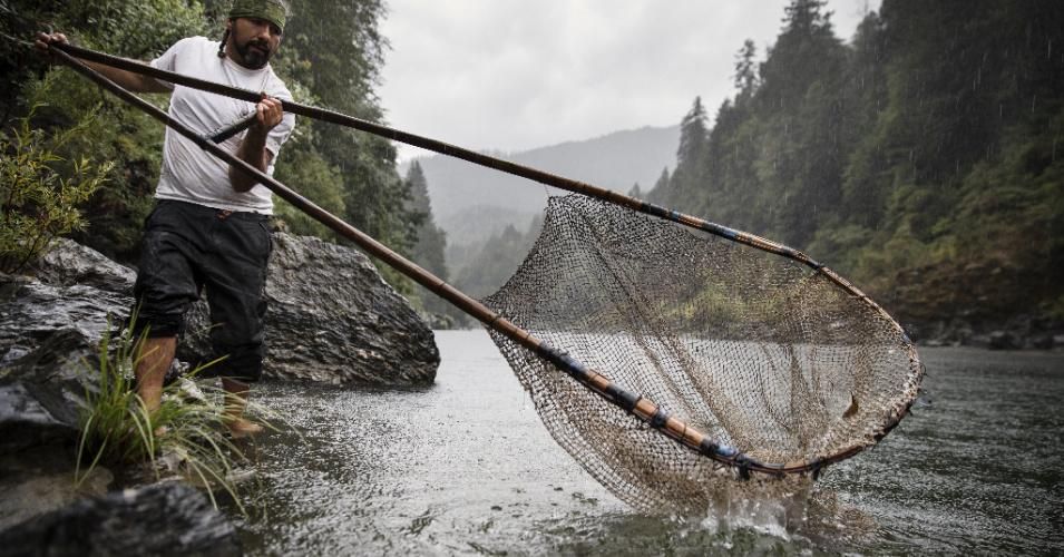 <p>Standing at the edge of the Klamath River in rural Northern California, a man from the Yurok Tribe uses a dip net to catch fish, the way his ancestors have done for centuries past. (Photo: Justin Lewis/Getty Images)</p>