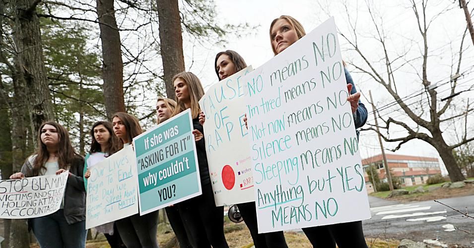 Students hold signs as they take part in a walkout at Lincoln-Sudbury Regional High School in Sudbury, Massachusetts on April 30, 2018 in response to the school's handling of a sexual assault case. 