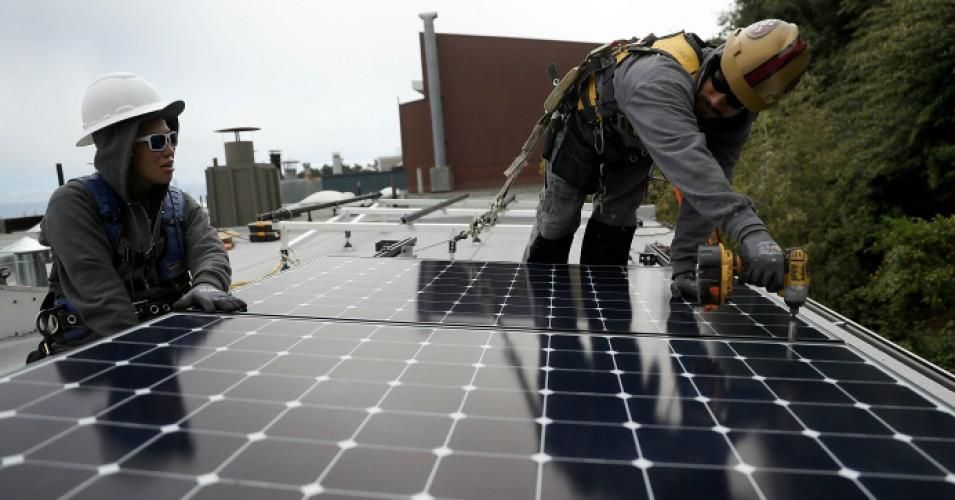 Solar workers install panels on the roof of a home in San Francisco, California on May 9, 2018. 