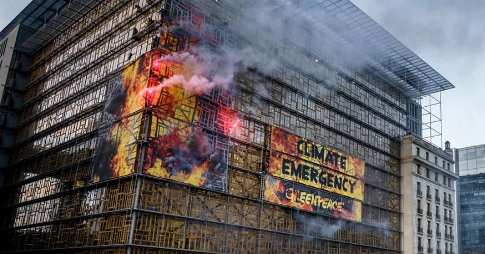 Greenpeace activists on Thursday wrap the E.U. summit venue in Brussels with images of giant flames, setting off clouds of smoke, flares and sounding a fire alarm to urge European government leaders to take immediate action to respond to the climate emergency.