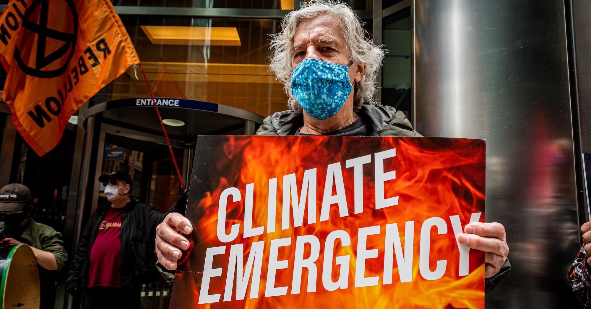 A climate activist with Stop the Money Pipeline holds a sign during a rally in midtown Manhattan on April 17, 2021. 