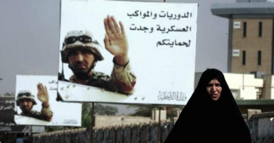 An Iraqi woman walks past billboards reading 'Patrols and military convoys are for your protection' in Baghdad in August 2006.