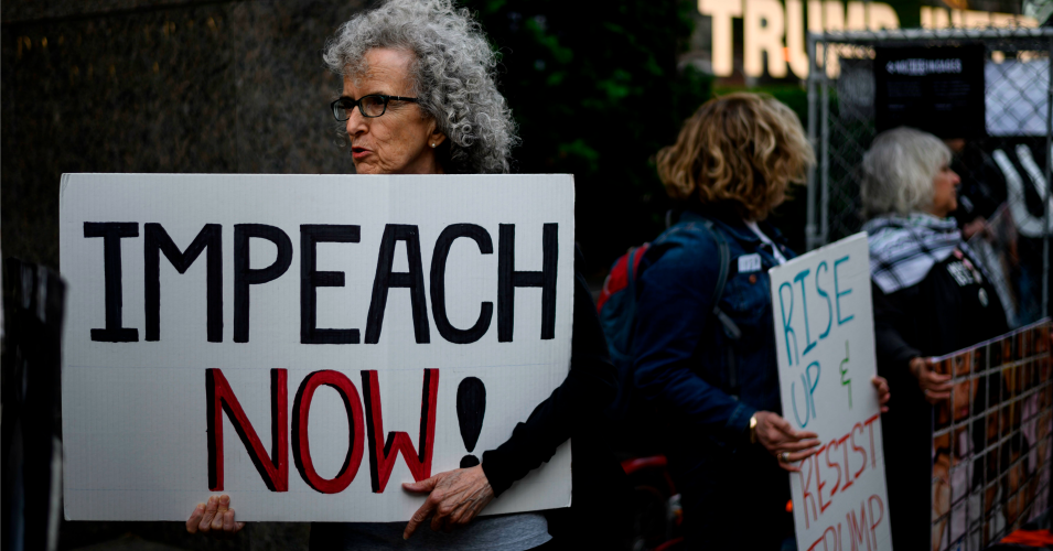 A demonstrator with a sign reading "impeach now" 
