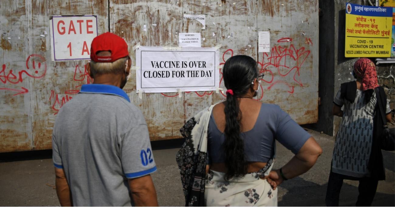 People stand near the gate of a vaccination center with a notice saying "vaccine is over, closed for the day" in Mumbai. (Photo: Ashish Vaishnav/SOPA Images/LightRocket via Getty Images)