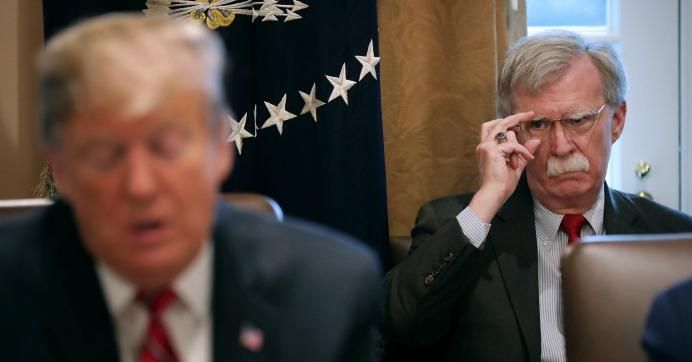 National Security Advisor John Bolton (R) listens to U.S. President Donald Trump talk to reporters
