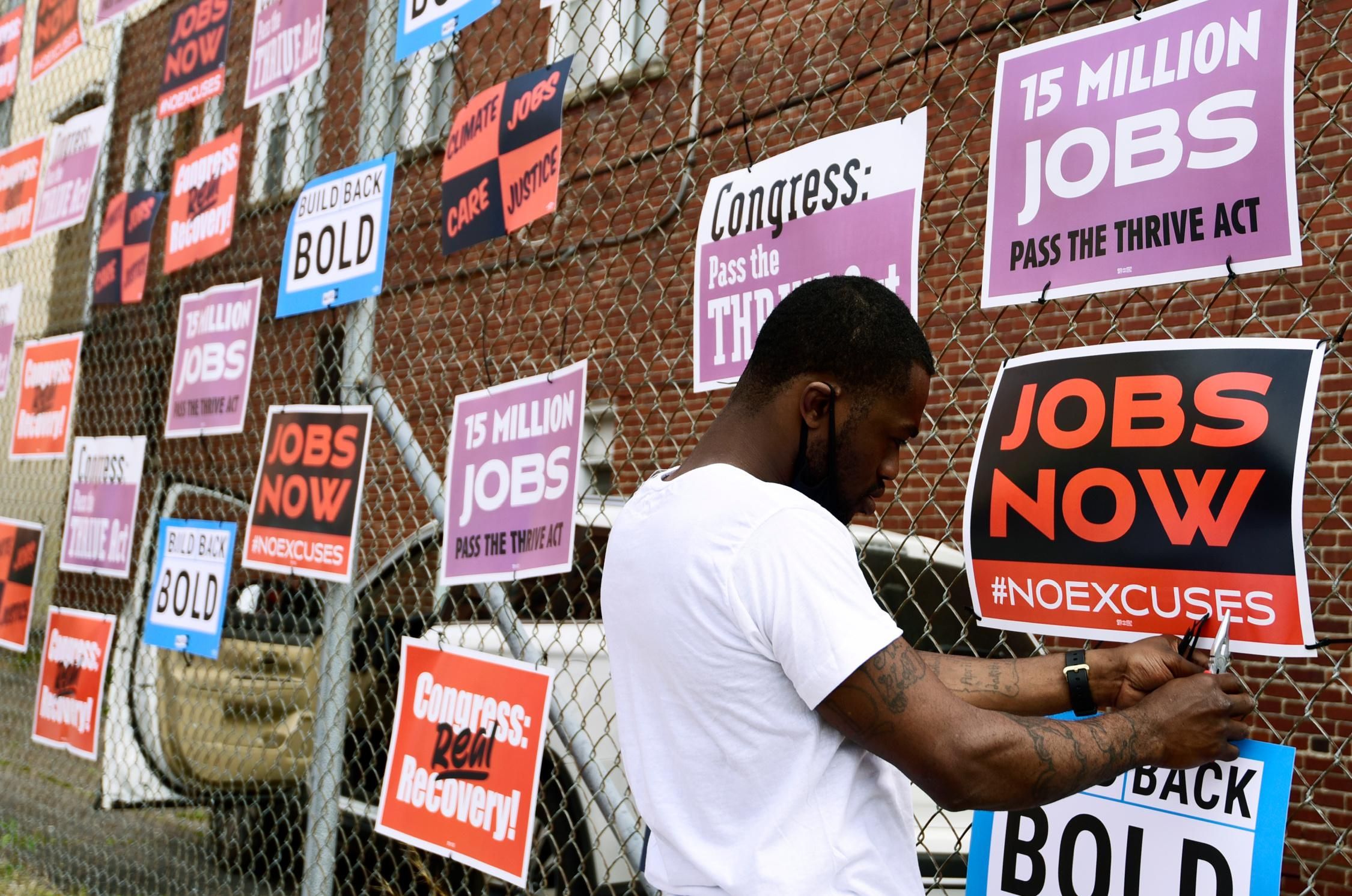 Derrick Davis, a member of West Virginia New Jobs Coalition, hangs up signage during a community gathering and job fair on April 8, 2021 in Charleston, West Virginia.