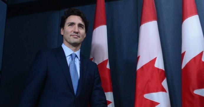 Prime Minister Justin Trudeau stands in front of Canadian flags