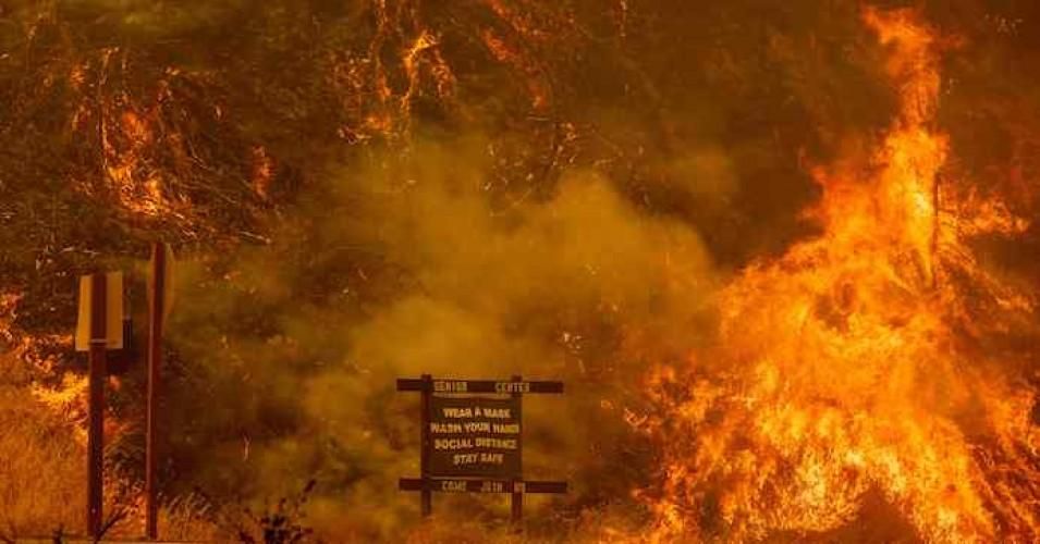 A sign warning people about Covid-19 is surrounded by flames during the Hennessey fire near Lake Berryessa in Napa, California on August 18, 2020. (Photo: by Josh Edelson/AFP via Getty Images)