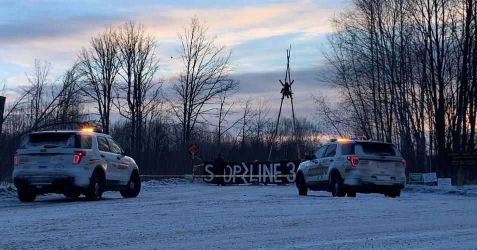 A water protector ascends nearly 40 feet in the air on a bi-pod blocking an entry road to Enbridge Line 3 worksites. (Photo: Giniw Collective)