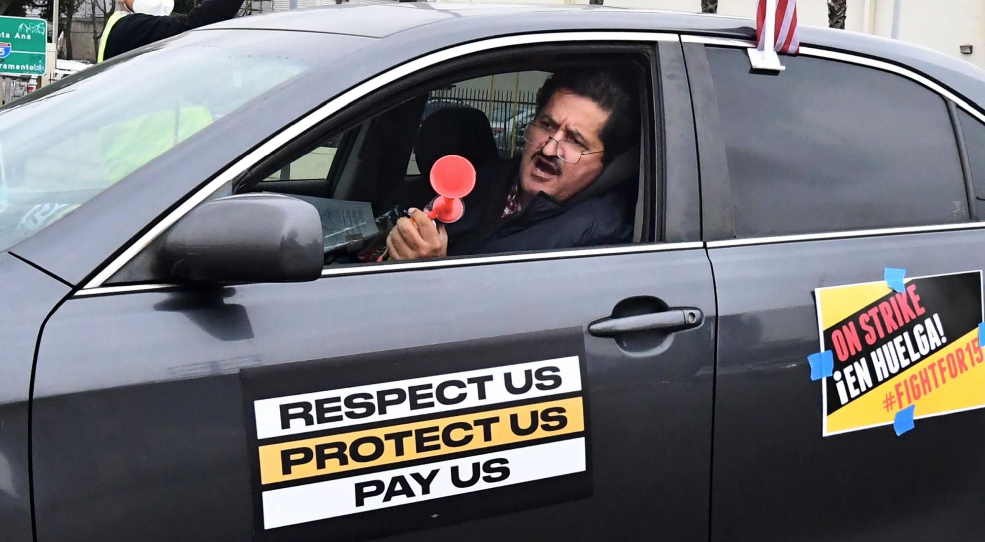 Food delivery driver Jorge Vargas honks a horn while driving his vehicle in a car caravan strike by fast food workers and their supporters on February 9, 2021 in Los Angeles. (Photo: Frederic J. Brown/AFP via Getty Images)