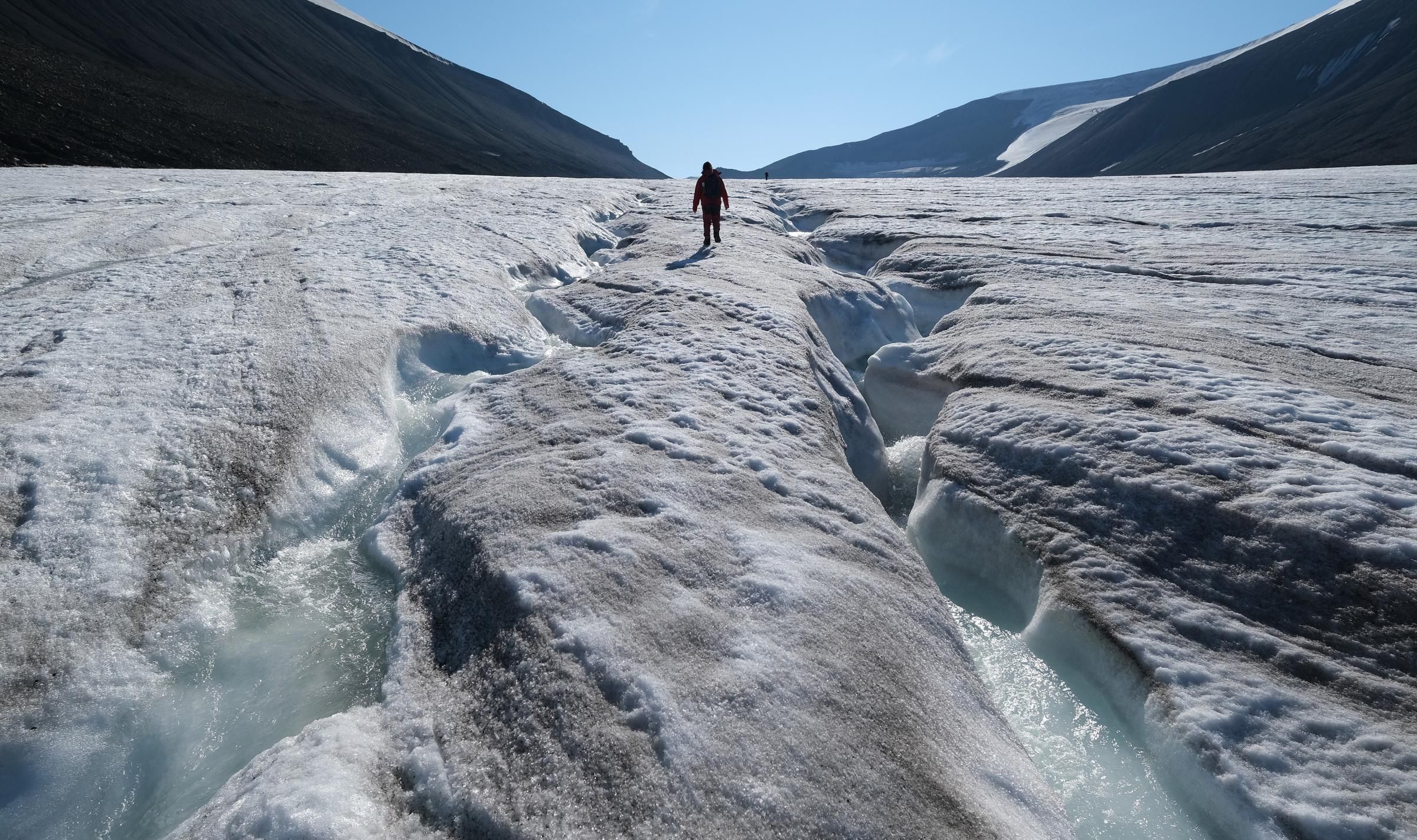 A hiker walks along winding channels carved by water on the surface of the melting Longyearbreen glacier during a summer heatwave on Svalbard archipelago on July 31, 2020 near Longyearbyen, Norway. (Photo: Sean Gallup via Getty Images)