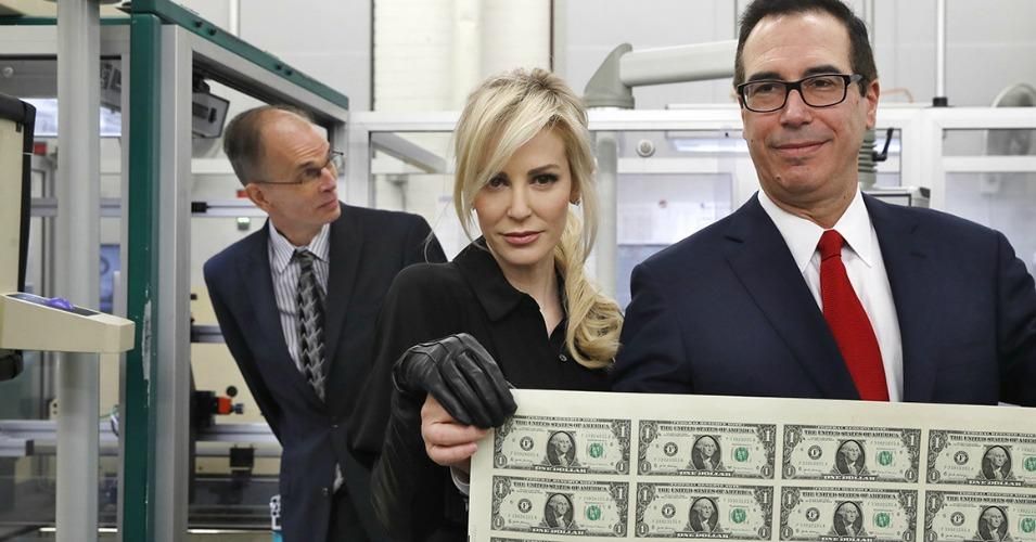 Treasury Secretary Steven Mnuchin and his wife, Louise Linton, hold up a sheet of new $1 bills, the first currency notes bearing his and U.S. Treasurer Jovita Carranza's signatures on Nov. 15 at the Bureau of Engraving and Printing in Washington.