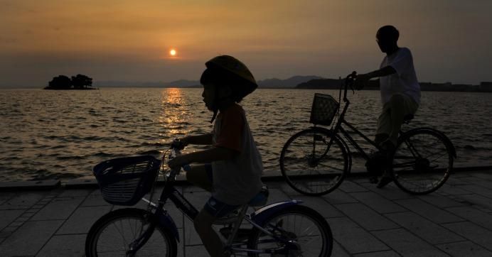 People cycle as the sun sets on Lake Shinji in Matsue, Shimane prefecture on July 25, 2008.