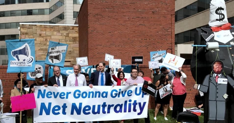 Rep. Jared Polis (D-Colo.), Sen. Ed Markey (D-Mass.), and Sen. Ron Wyden (D-Ore.) hold up a banner at Thursday's rally for net neutrality in Washington, D.C. 