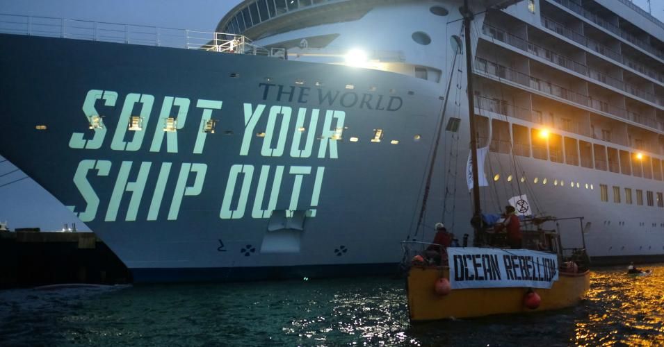 Members of a new climate movement, Ocean Rebellion, protest in the United Kingdom's Falmouth Harbor by projecting slogans on the bow of the cruise ship named The World. 