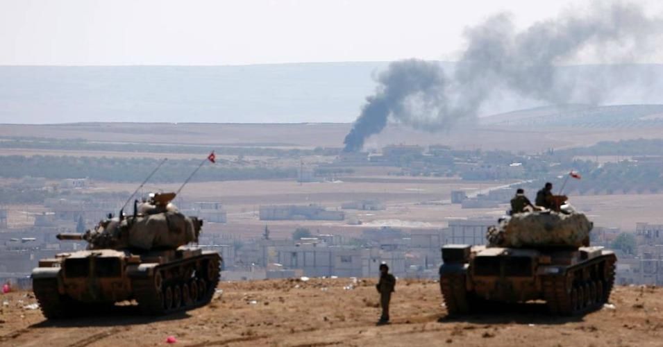 Smoke rises from the Syrian town of Kobani as Turkish army tanks take position on the Turkish side of the border.