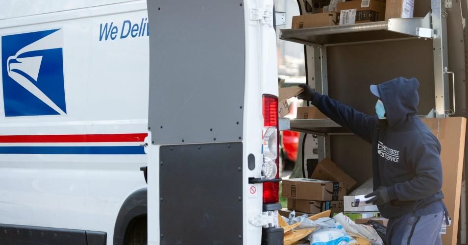 A mailman wearing a mask and gloves loads a postal truck with packages at a United States Postal Service (USPS) post office location in Washington, D.C. on April 16, 2020.