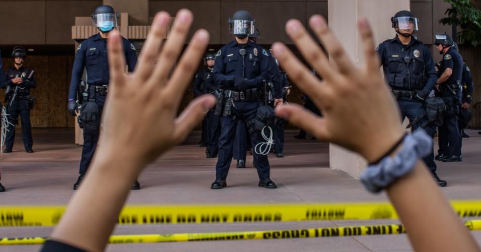 During a peaceful protest over the killing of George Floyd, a demonstrator holds her hands up while kneeling in front of police officers on June 1, 2020 in Anaheim, California. (Photo: Apu Gomes/AFP via Getty Images)