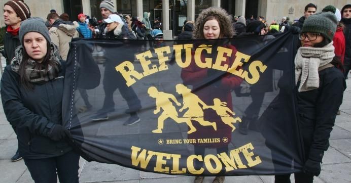Women hold a flag saying 'Refugees Welcome' as thousands of Canadians take part in a massive protest against President Trump's travel ban on Muslims