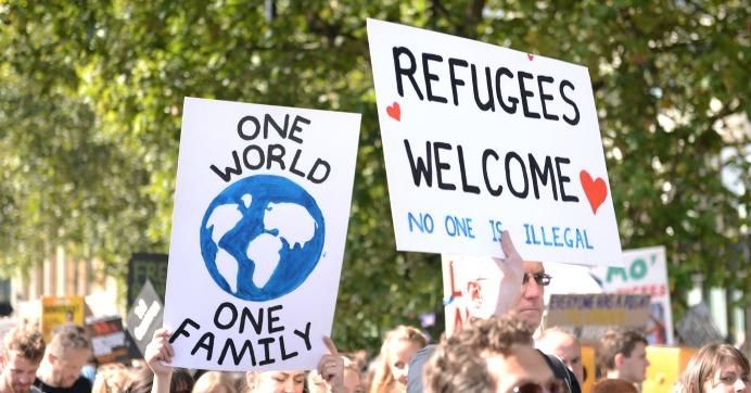 Demonstrators hold signs in support of refugees