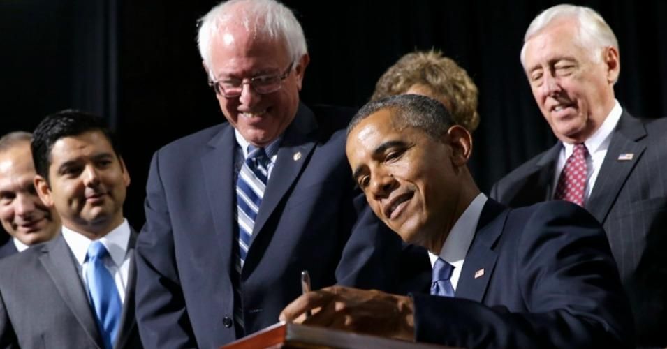 Sen. Bernie Sanders (I-Vt.) smiles as then-President Barack Obama signs a bill into law.
