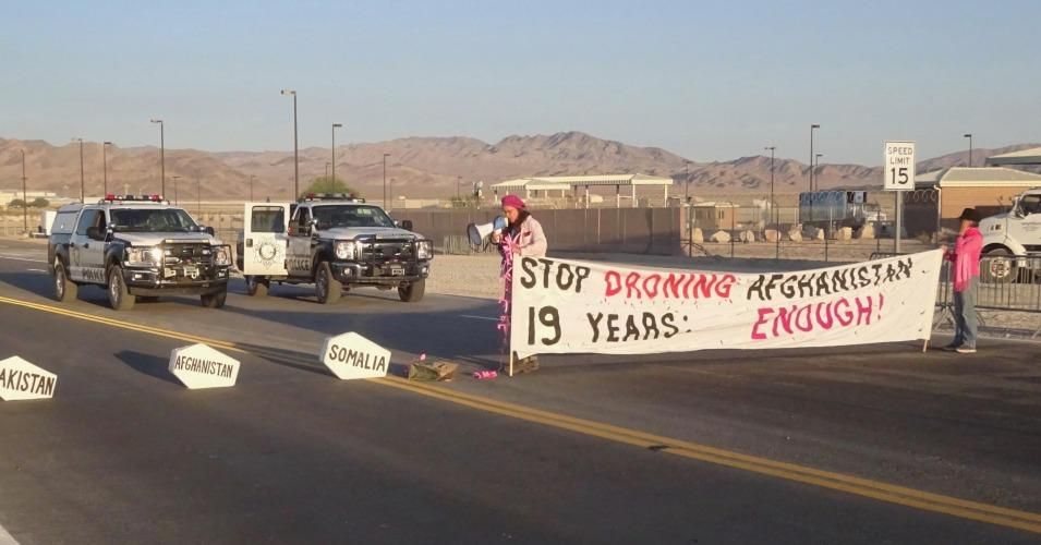 CodePink activists Maggie Huntington and Toby Blomé unfurl a banner and block traffic during an anti-drone protest at Creech Air Force Base in Clark County, Nevada on October 2, 2020 (Photo: Codepink)