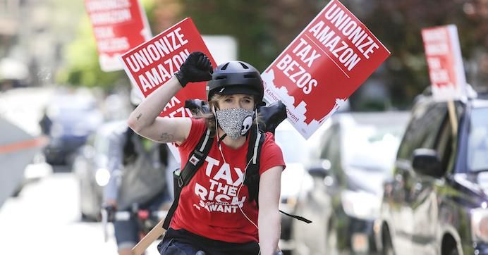Protesters cycle around the block as they participate in a "car caravan" protest at the Amazon Spheres to demand the Seattle City Council tax the city's largest businesses in Seattle on May 1, 2020.