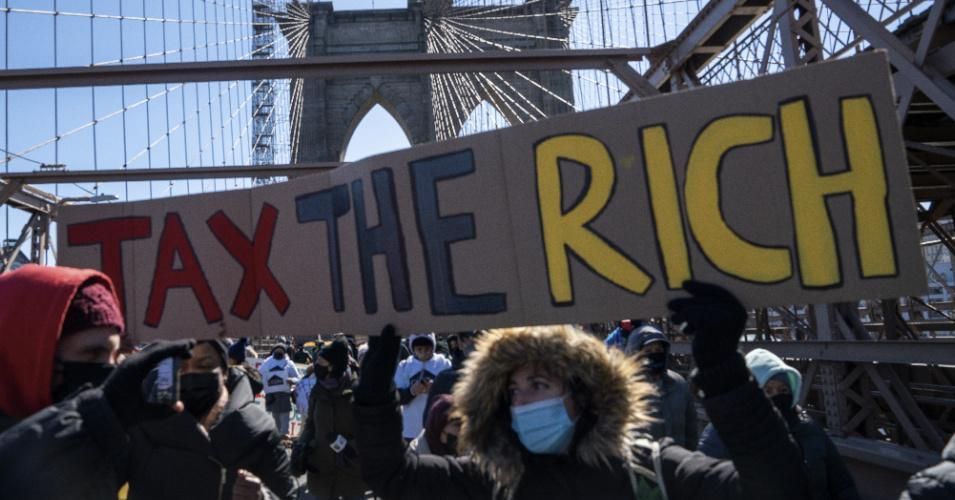 Protestors march across the Brooklyn Bridge holding a sign to "tax the rich" to demand funding for excluded workers in the New York State budget on March 5, 2021 in New York City. The march led by undocumented workers and those recently released from incarceration. Many of these excluded workers have been unable to access unemployment benefits, stimulus checks, and other economic assistance programs intended to help working families affected by the COVID-19 pandemic and the ensuing economic crisis. (Photo: 