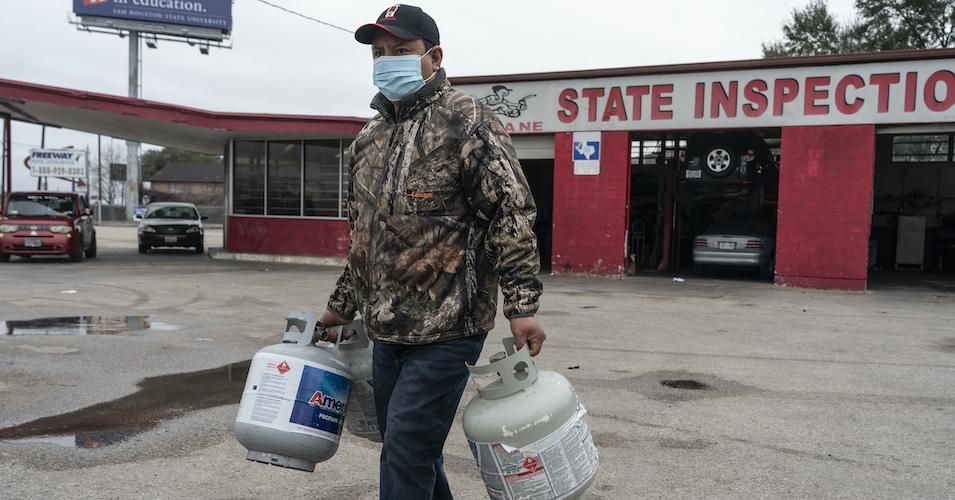 A person carries empty propane tanks, bringing them to refill at a propane gas station after winter weather caused electricity blackouts on February 18, 2021 in Houston. Winter storm Uri brought severe temperature drops causing a catastrophic failure of the power grid in Texas. About two million people are without electricity throughout Houston. (Photo: Go Nakamura/Getty Images)