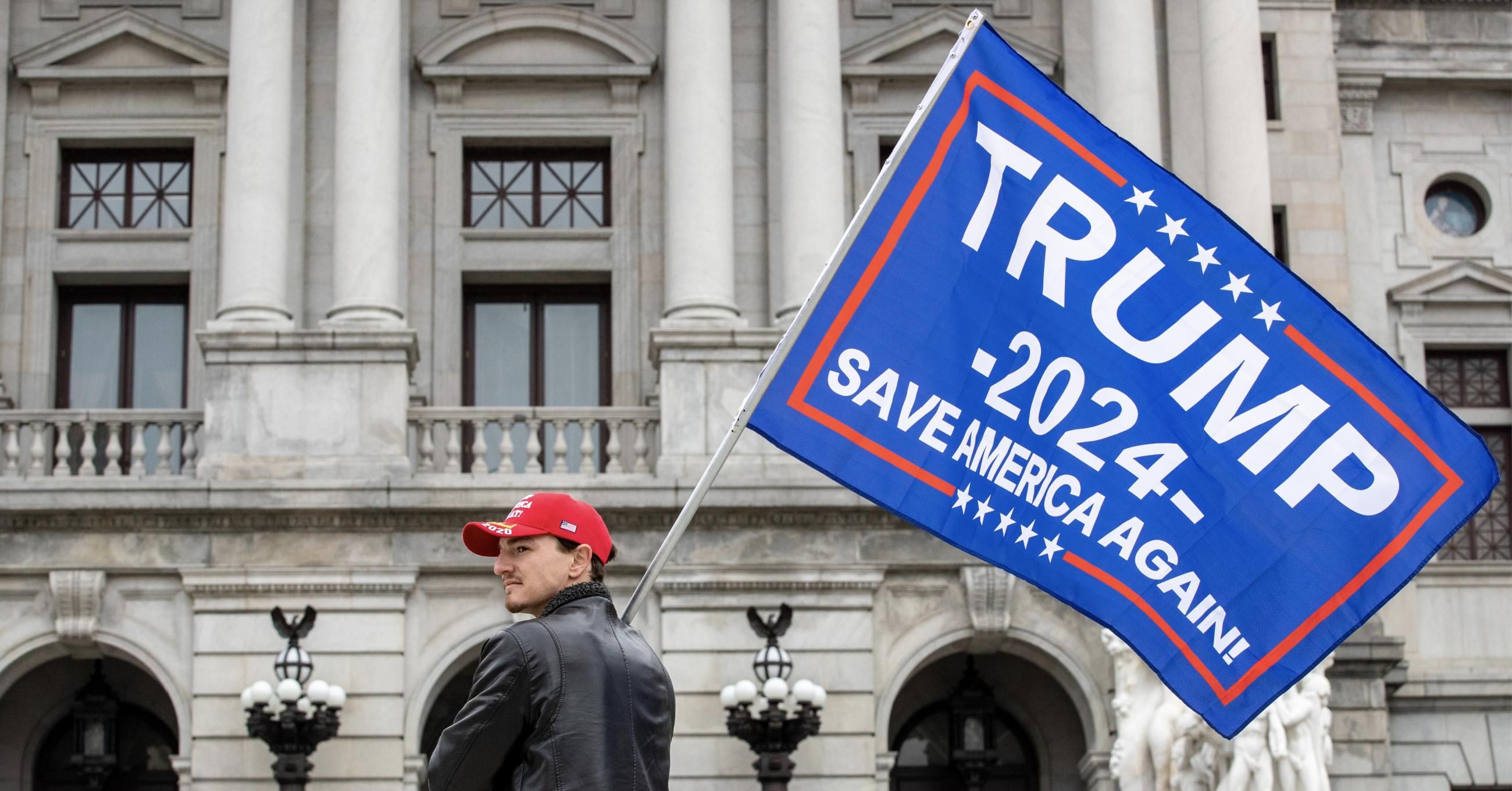 A protester holds a Trump 2024 flag in front of the Pennsylvania State Capitol on February 27, 2021. (Photo: Paul Weaver/SOPA Images/LightRocket via Getty Images)