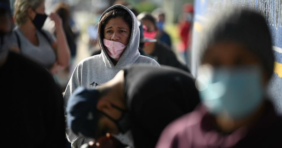 Local residents who have been financially impacted by the coronavirus pandemic wait in line at a Thanksgiving meal take home kit food distribution organized by the L.A. Mission, November 20, 2020, outside Compton Avenue Elementary School in Los Angeles, California.