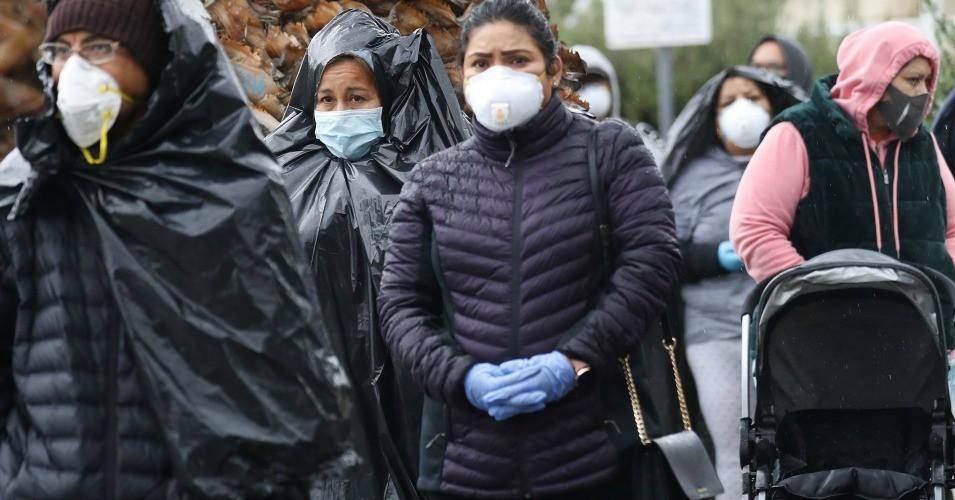 Juana Gomez wears a face mask while using a trash bag to protect against the rain, as she waits in line to receive food at a Food Bank distribution for those in need as the coronavirus pandemic continues on April 9, 2020 in Van Nuys, California.