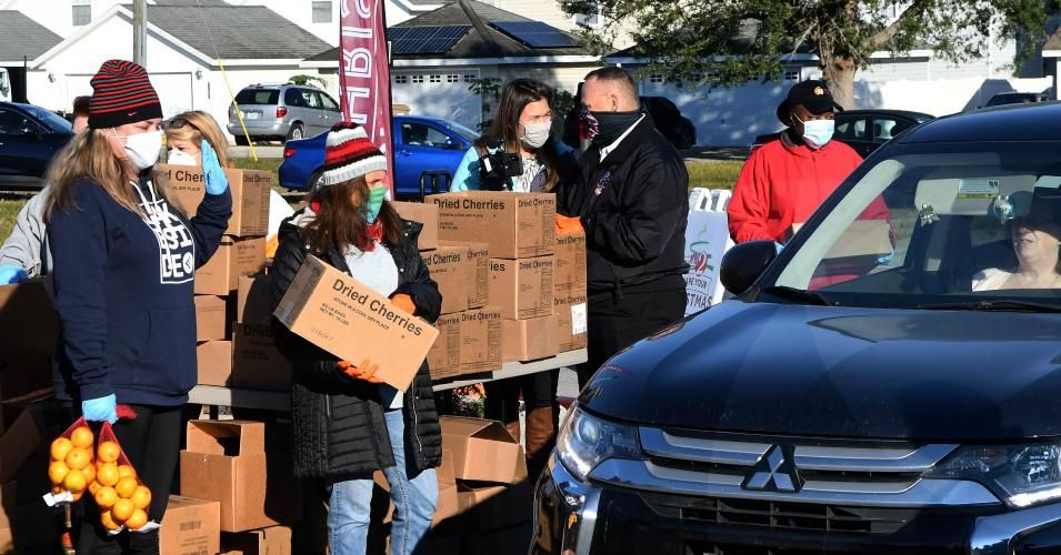 Volunteers load boxes of food assistance into cars at a food distribution event sponsored by the Second Harvest Food Bank of Central Florida, Faith Neighborhood Center, and WESH 2 at Hope International Church on December 9, 2020 in Groveland, Florida.