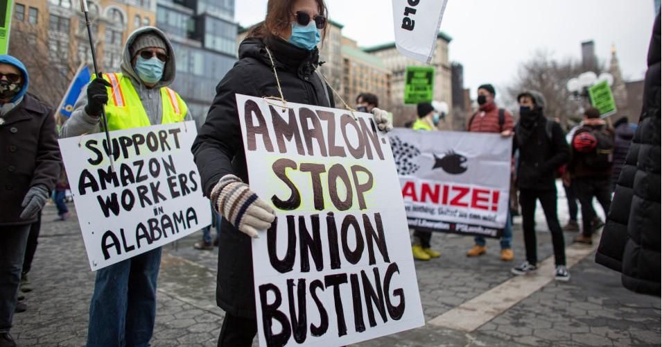 People hold placards during a protest in support of Amazon workers in Union Square, New York on February 20, 2021. 