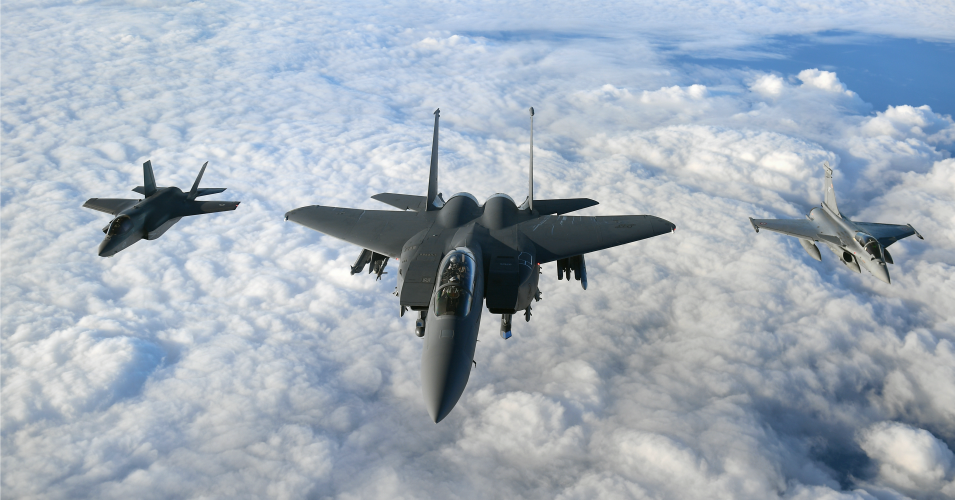 An RAF F-35B Lightning stealth jet, a United States Air Force F-15 Strike Eagle, and a French Air Force Rafale fly in formation over the English Channel during Operation Point Blank.