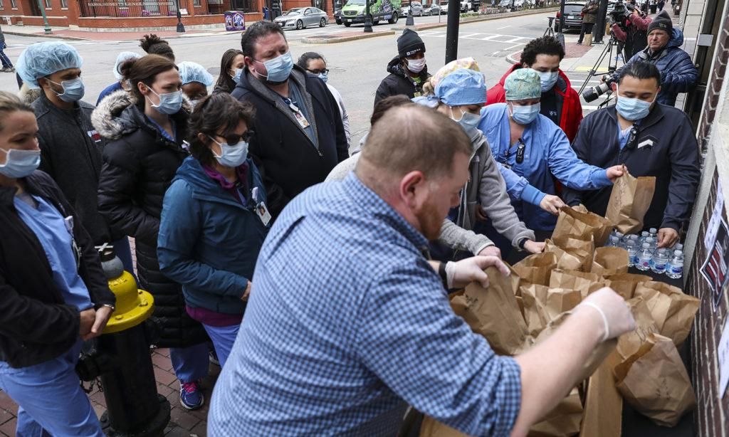 Matt Hart, beverage director at Harvard Gardens, helps to distribute bagged lunches to Massachusetts General Hospital employees in Boston on April 1, 2020. The restaurant has offered help by providing free lunches for medical professionals. (Photo: Erin Clark/The Boston Globe/Getty Images)