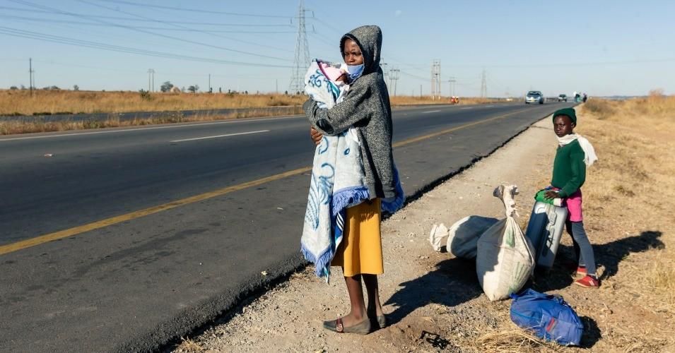 A stranded mother carries her child by a road with little traffic as she awaits transport to get into the central business district of Harare, Zimbabwe on June 2, 2020