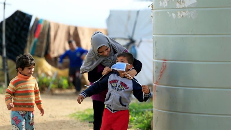 A Syrian refugee woman puts a face mask on a boy as a precaution against the spread of coronavirus, in al-Wazzani area, in southern Lebanon on March 14, 2020 (Photo: Ali Hashisho/Reuters)