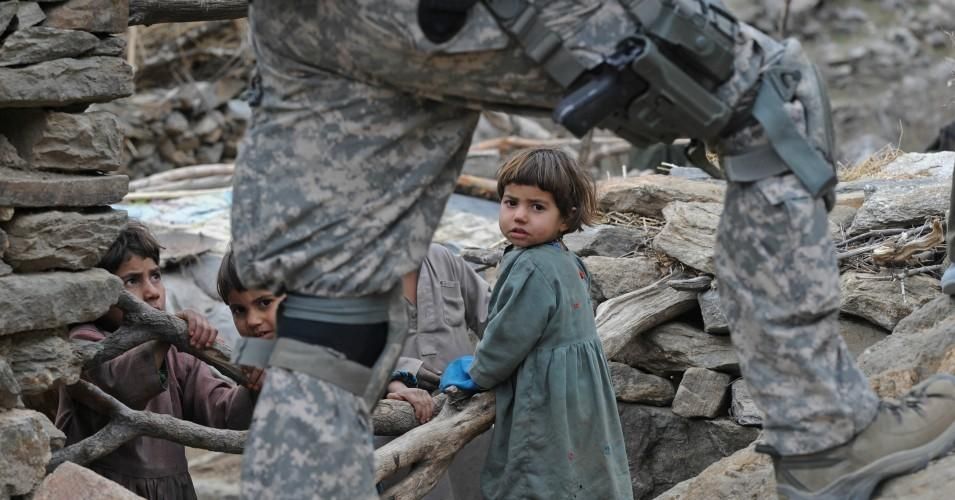 Afghan children look on as a U.S. soldier from the Provincial Reconstruction team (PRT) Steel Warriors patrols in the mountains of Nuristan Province on Dec. 19, 2009. 
